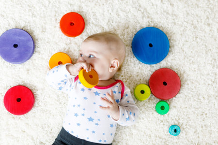 Cute baby girl playing with colorful wooden rattle toy