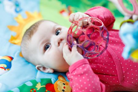 Cute baby girl playing with colorful rattle toyの写真素材