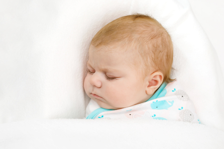 Cute little newborn baby girl sleeping wrapped in blanketの写真素材