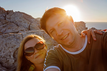 Happy traveling couple making selfie mountains background at sunrise, sunny summer colors, romantic...