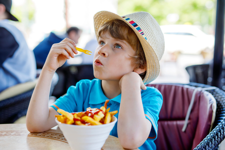 Cute healthy preschool kid boy eats french fries potatoes with ketchupの写真素材