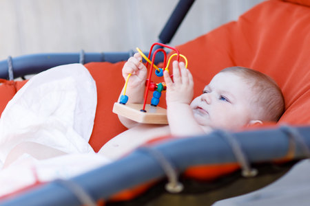 adorable newborn baby playing with colorful wooden educational rattle toyの写真素材