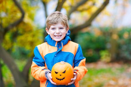 happy cute little kid boy with halloween pumpkin lantern on autumnの写真素材