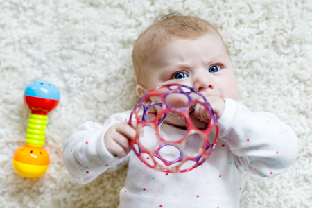 Cute baby girl playing with colorful rattle toyの写真素材