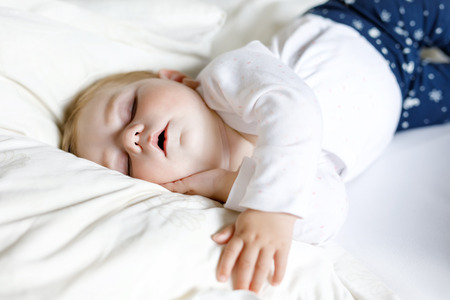 Cute adorable baby girl of 6 months sleeping peaceful in bedの写真素材