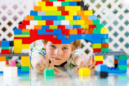 Little blond child and kid boy playing with lots of colorful plastic blocks.の写真素材