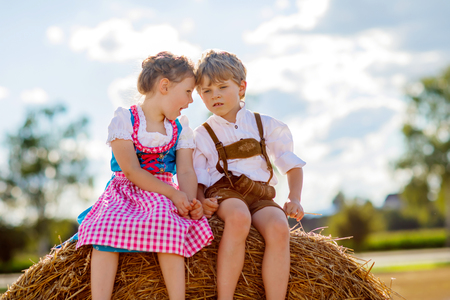 Two kids, boy and girl in traditional Bavarian costumes in wheat fieldの写真素材