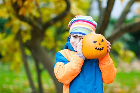 happy cute little kid boy with halloween pumpkin lantern on autuの写真素材