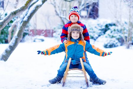 Two little kid boys enjoying sleigh ride in winterの写真素材