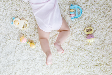 Close-up of baby body and legs with lots of colorful rattle toys.の写真素材