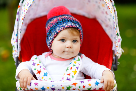Cute little beautiful baby girl of 6 months sitting in the stylish pram or stroller and waiting for momの写真素材