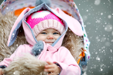 Cute little beautiful baby girl sitting in the pram or stroller on autumn dayの写真素材
