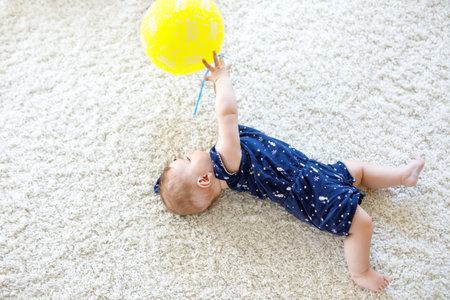 Cute baby playing with red air balloon, crawling, grabbing