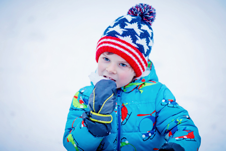 Happy kid boy having fun with snow in winterの写真素材