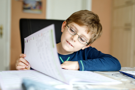 Happy school kid boy at home making homeworkの写真素材