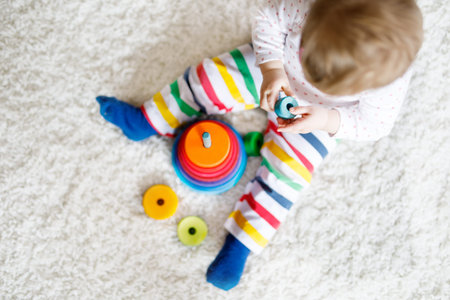 Adorable cute beautiful little baby girl playing with educational colorful wooden rainboy toy...