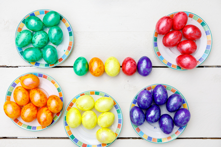 Easter eggs on wooden background. Colorful eggs in different colors - red, yellow, orange, purple and green.の写真素材