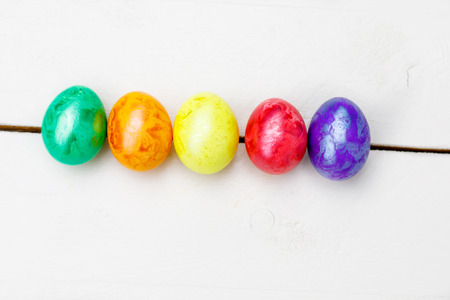 Easter eggs on wooden background. Colorful eggs in different colors - red, yellow, orange, purple and green.の写真素材
