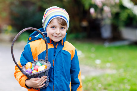 Cute adorable little kid boy making an egg hunt on Easter.