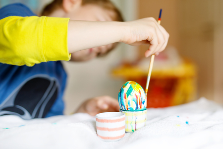 Close-up of little kid hands coloring eggs for Easter holidayの写真素材