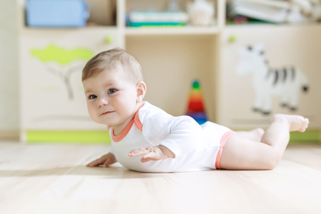 Cute baby girl learning crawling and sitting in children roomの写真素材