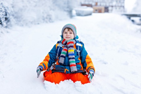Happy kid boy having fun with snow on way to schoolの写真素材