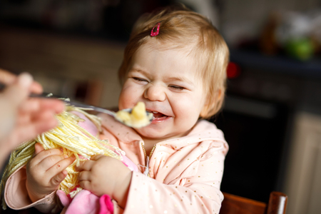 Adorable baby girl eating from spoon mashed vegetables and puree. food, child, feeding and people conceptの写真素材