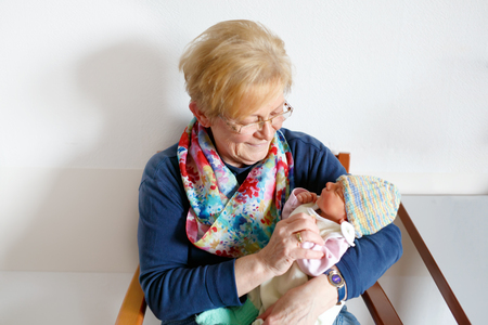 Grandmother holding newborn baby grandchild girl on armsの写真素材