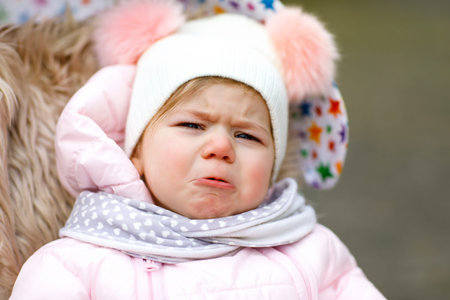 Sad crying hungry baby girl sitting in the pram or stroller on cold dayの写真素材