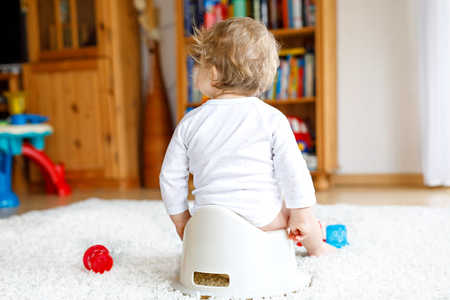 Closeup of legs of cute little 12 months old toddler baby girl child sitting on potty.の写真素材