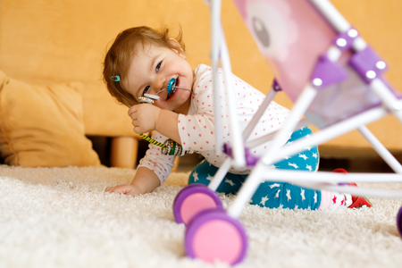 Happy little toddler baby girl playing hide and seek at home. Child having fun with parents or siblingsの写真素材
