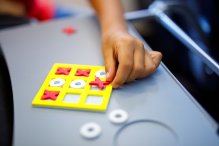 Tic tac toe game. Leisure activity for kids and adults. At home, traveling, on plane. Closeup of hands of child playing gameの写真素材