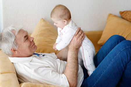 Happy grandfather holding adorable baby girl grandchild on arms.の写真素材