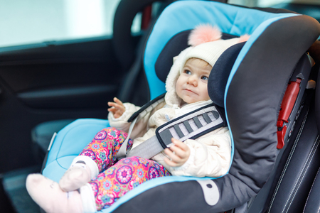 Adorable baby girl with blue eyes sitting in car seat. Toddler child in winter clothes going on family vacations and jorneyの写真素材