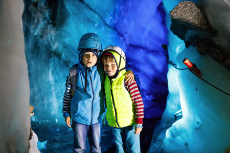 Two little boys with safety helmets and clothing with mountains landscape backgrounds. Kids hiking...