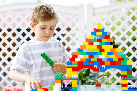 Little blond child and kid boy playing with lots of colorful plastic blocks.の写真素材