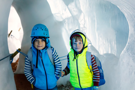 Two little boys with safety helmets and clothing with mountains landscape backgrounds. Kids hiking...