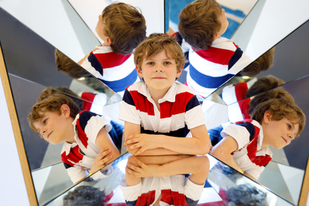 Little kid boy having fun with experiments with mirrors in a musem. Portrait of happy smiling school child.の写真素材