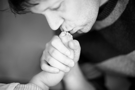 Father kissing foot of newborn baby.の写真素材