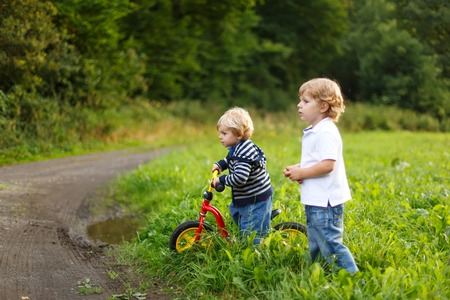 Two little brother boys playing near forest on summer evening. Cute siblings playing together.の写真素材