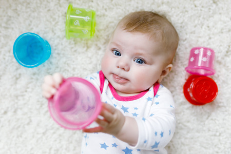 Cute adorable newborn baby playing with colorful educational rattle toyの写真素材
