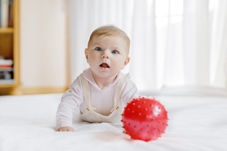 Cute baby playing with red gum ball, crawling, grabbing
