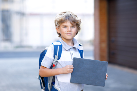 Happy little kid boy with backpack or satchel. Schoolkid on the way to school. Healthy adorable child outdoors With empty chalk desk for copyspace. Back to school.の写真素材