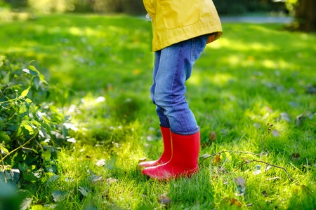Little child in colorful rain boots. Close-up of school or preschool legs of kid boy or girl in different rubber boots, jeans and jackets. Footwear for rainy fallの写真素材
