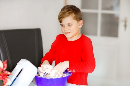 Cute little boy baking gingerbread Christmas cookies at home. Adorable blond child having fun in domestic kitchen. Traditional leisure with kids on Xmas.の写真素材