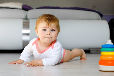 Little cute baby girl learning to crawl. Healthy child crawling in kids room. Smiling happy healthy...
