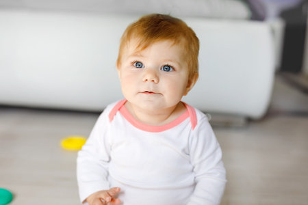 Adorable baby girl playing with educational toys in nursery. Happy healthy child having fun with...