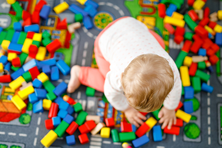 Adorable baby girl playing with educational toys . Happy healthy child having fun with colorful different wooden blocks at home in domestic room. Baby learning colors and formsの写真素材