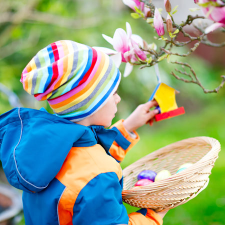 Cute adorable little kid boy making an egg hunt on Easter. Happy child searching and finding...