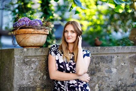 Beautiful young woman with long hairs in summer dress going for a walk in German city. Happy girl enjoying walking in cute small fachwerk town with old houses in Germany.の写真素材